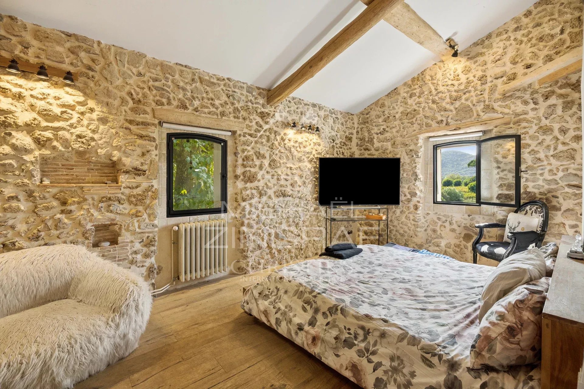 Chambre de la magnanerie Chambre d'une demeure en pierre avec lit, fenêtres et décoration rustique.