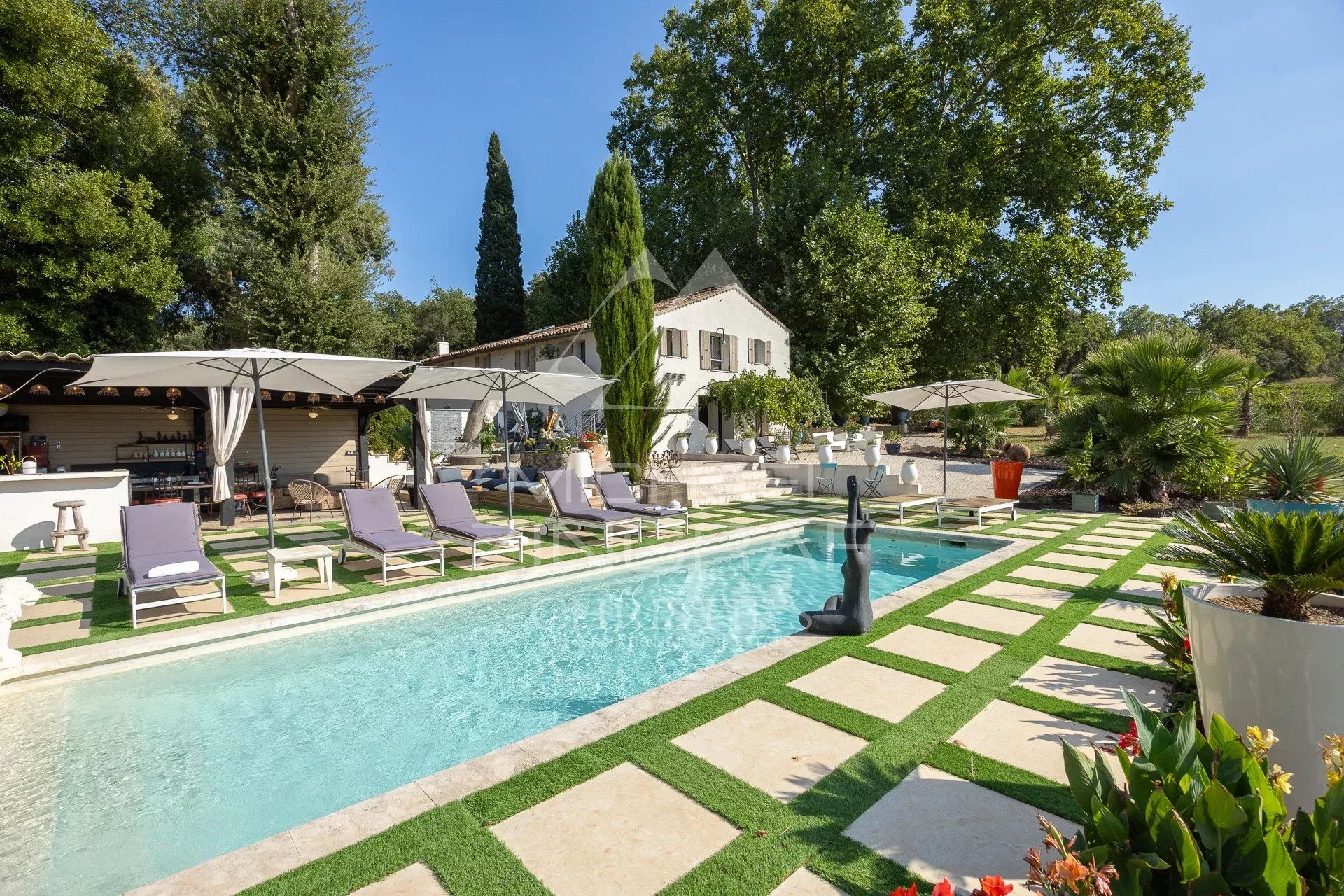 Demeure de caractère avec piscine Demeure avec piscine et chaises longues, entourée de verdure et d'arbres.