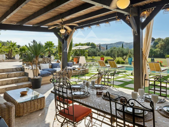 Terrasse extérieure avec mobilier de jardin et piscine, entourée de verdure et de vignes.