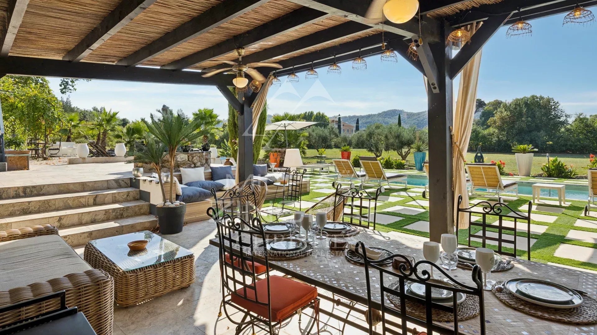 Demeure avec piscine et terrasse Terrasse extérieure avec mobilier de jardin et piscine, entourée de verdure et de vignes.