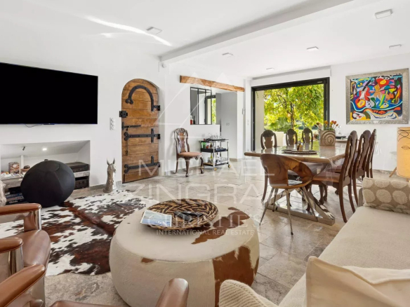 Intérieur d'une demeure avec salon, table à manger et accès à l'extérieur, décoré avec des œuvres d'art.
