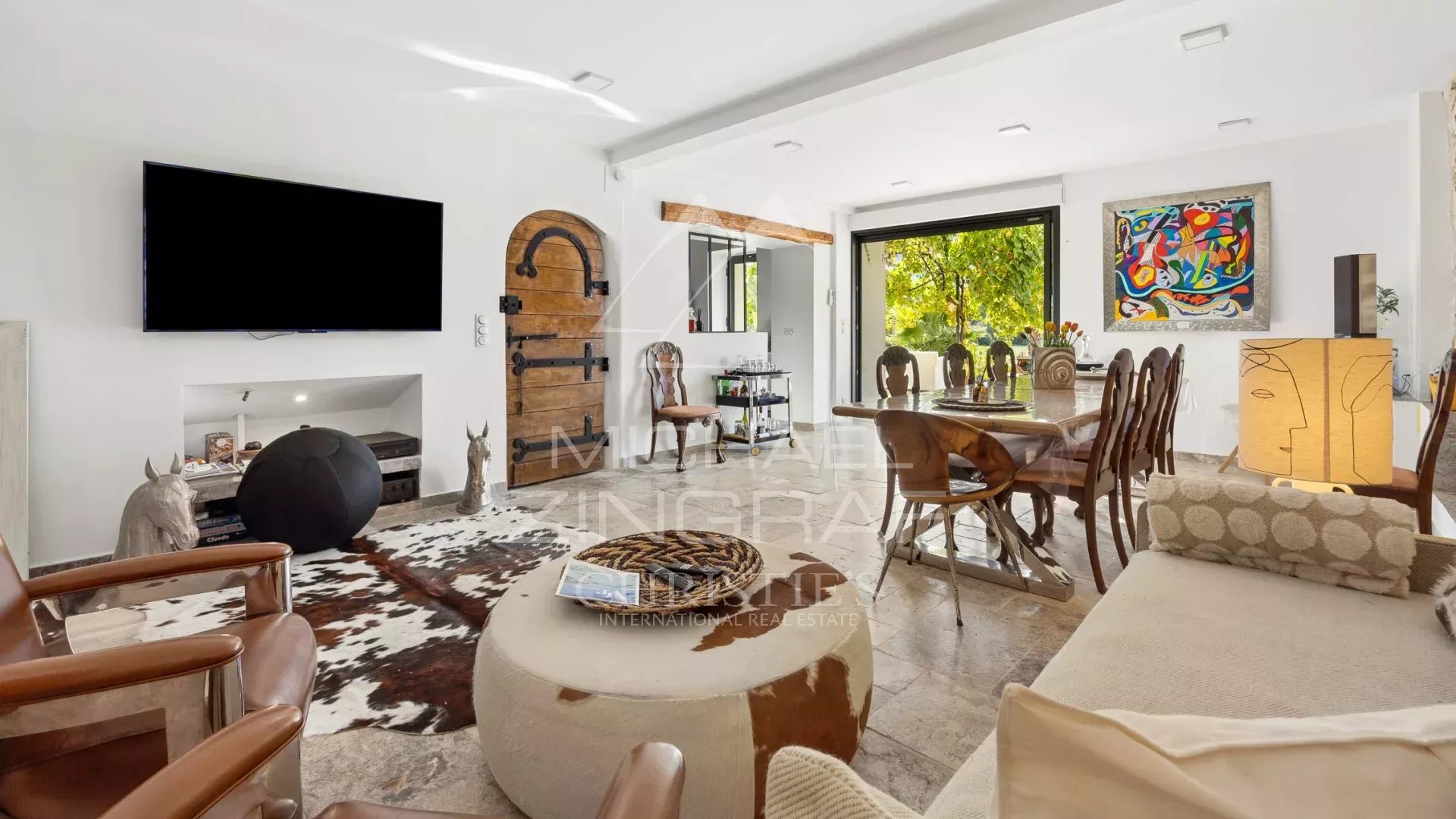 Intérieur d’une magnanerie réhabilitée Intérieur d'une demeure avec salon, table à manger et accès à l'extérieur, décoré avec des œuvres d'art.