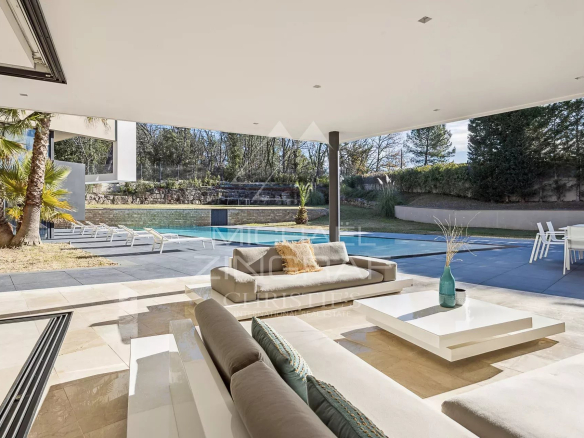 Intérieur d'une villa contemporaine avec salon lumineux donnant sur la piscine et le jardin.