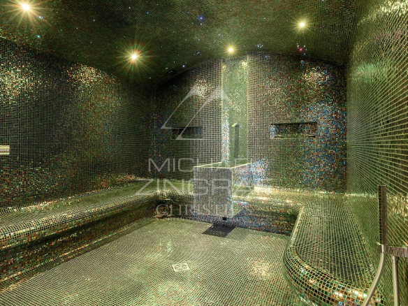 Intérieur d'un hammam décoré de mosaïques colorées, avec bancs et éclairage doux.