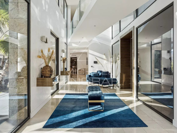 Intérieur d'une villa contemporaine avec un séjour lumineux et des baies vitrées.