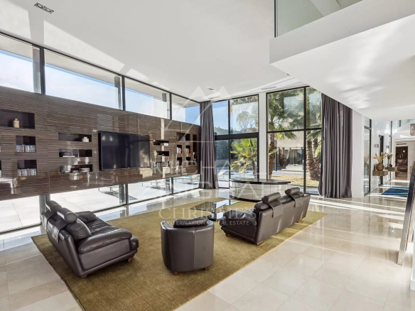 Intérieur d'une villa contemporaine avec un salon spacieux et des baies vitrées.