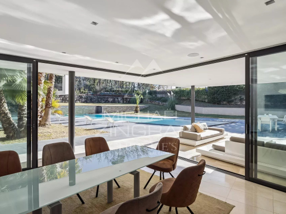 Intérieur d'une villa contemporaine avec salle à manger et vue sur l'extérieur.