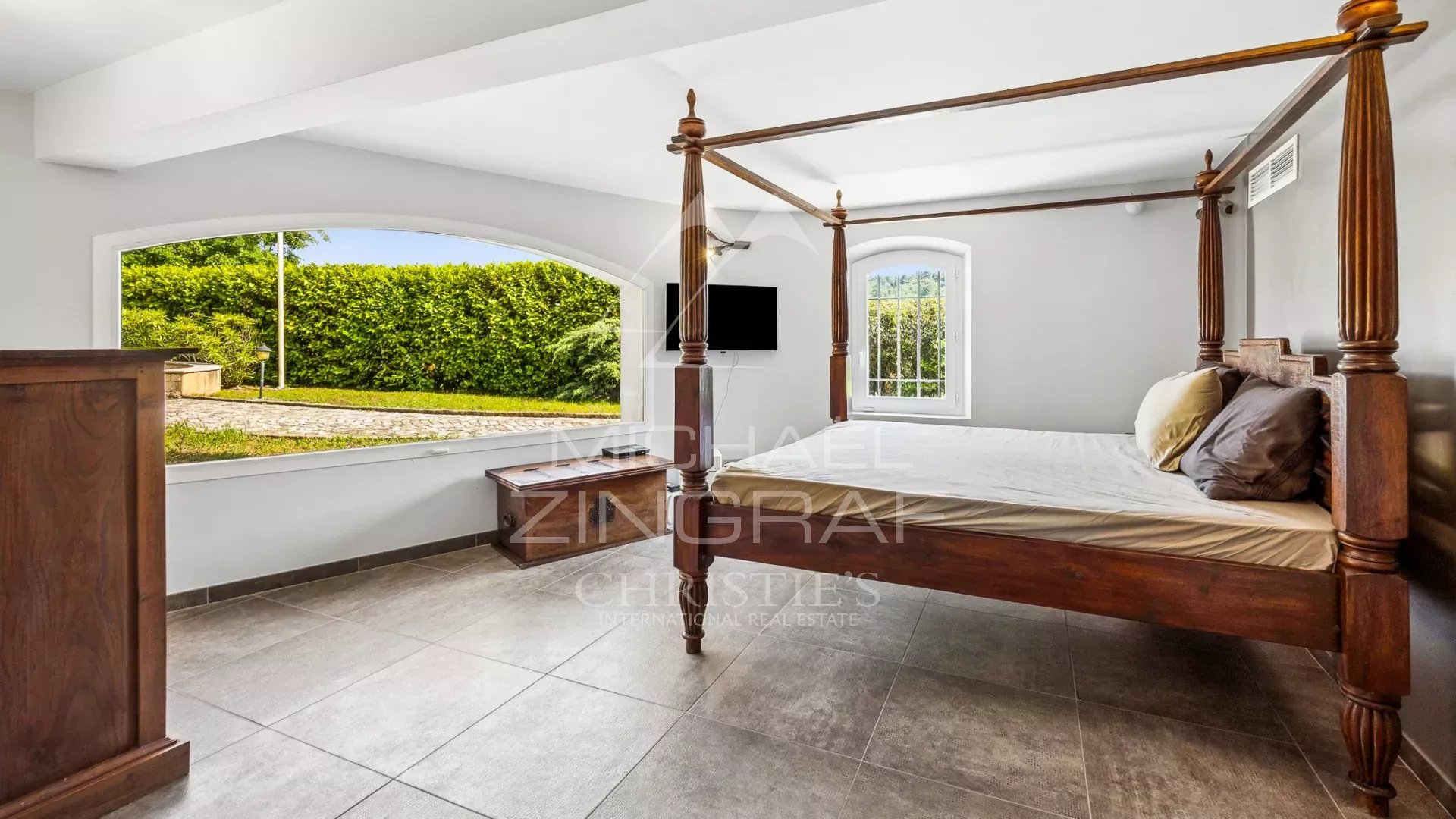 Spacious room with a four-poster bed and a view of the garden.