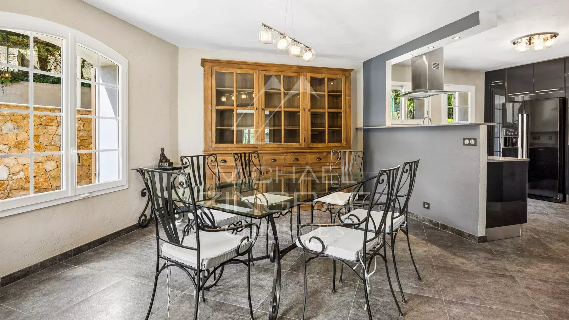 Dining room with glass table and wrought iron chairs in a family villa.