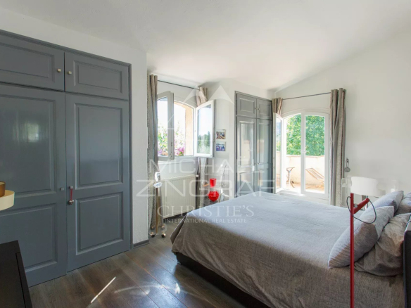 Chambre d'une villa provençale avec lit et fenêtres donnant sur un jardin.