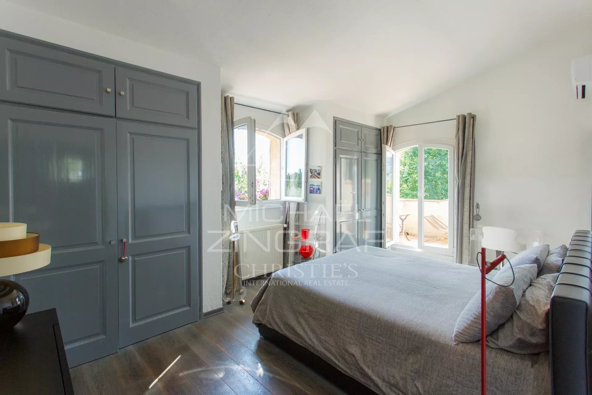 Chambre de villa provençale Chambre d'une villa provençale avec lit et fenêtres donnant sur un jardin.