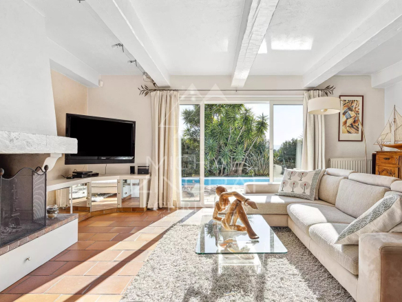 Intérieur lumineux d'une villa provençale avec salon, cheminée et vue sur jardin.