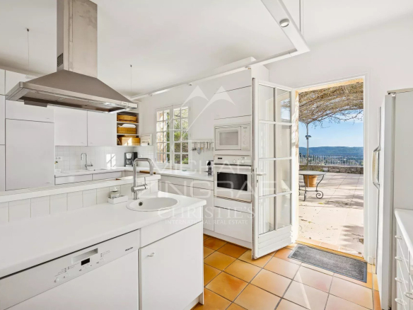 Cuisine moderne avec vue sur une terrasse et paysage en arrière-plan.