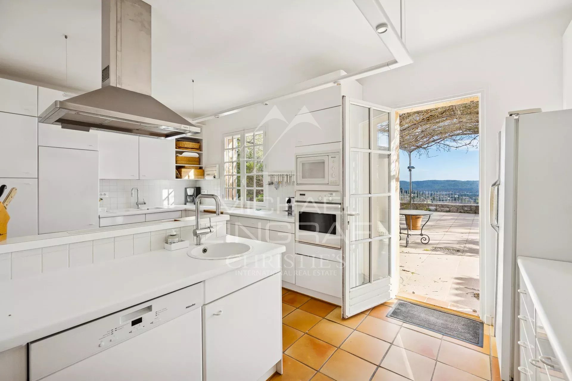 Cuisine de villa à Fayence Cuisine moderne avec vue sur une terrasse et paysage en arrière-plan.