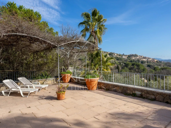 Terrasse ensoleillée avec chaises longues et vue sur le village de Fayence.