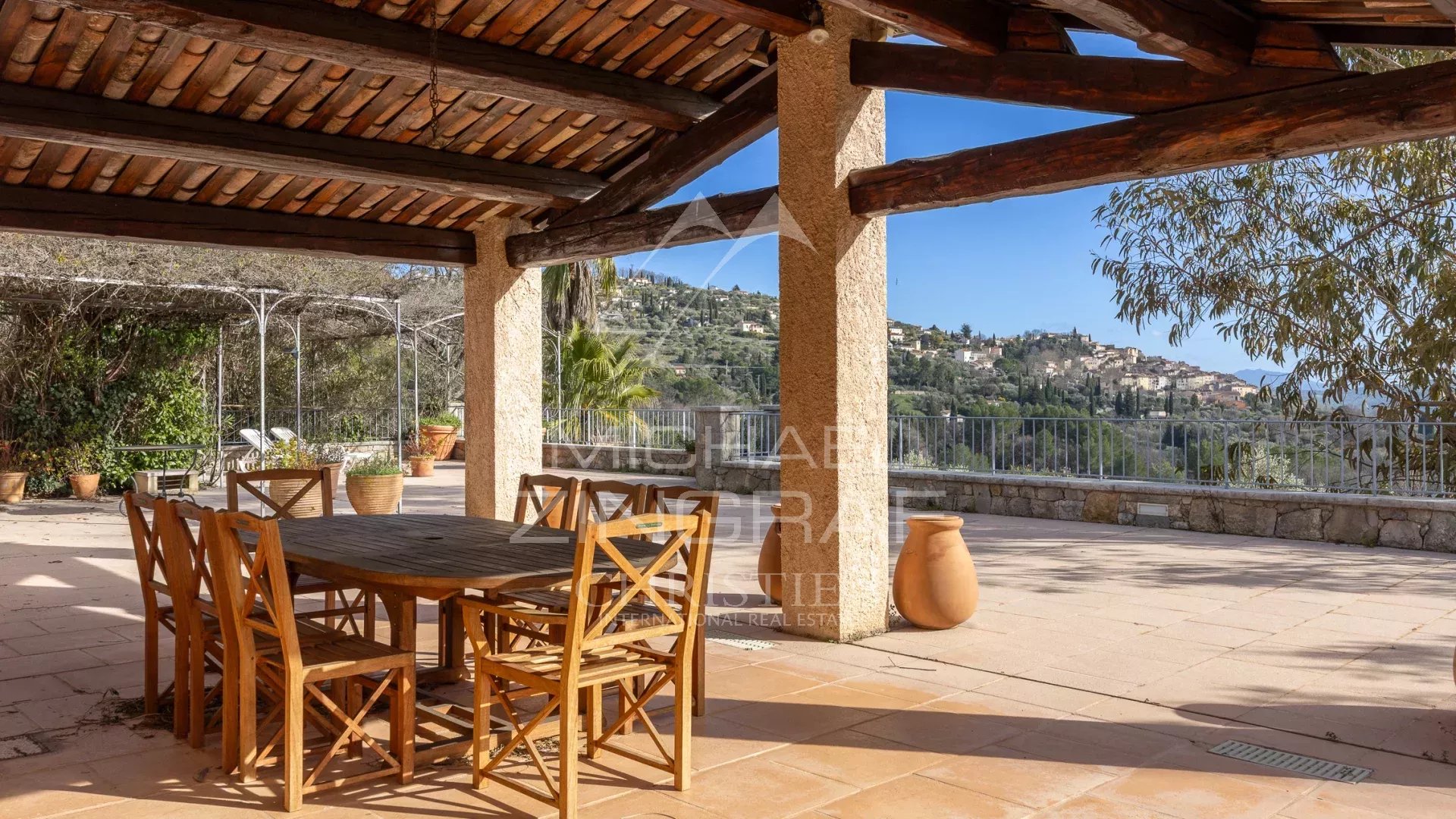 Terrasse avec vue à Fayence Terrasse ensoleillée avec table et chaises en bois, vue sur le village de Fayence.