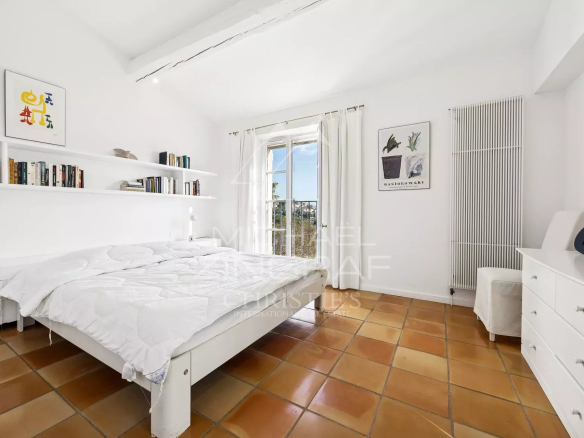 Chambre lumineuse avec lit double et vue sur l'extérieur, décorée simplement.