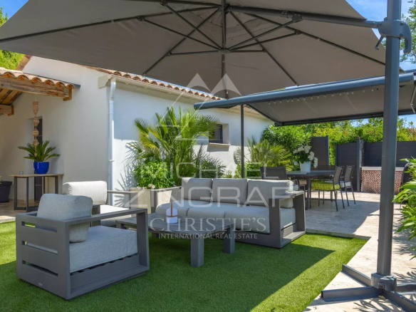 Terrasse d'une villa moderne à Grasse avec mobilier de jardin et parasol.