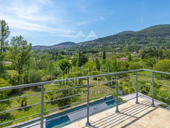 Vue depuis la terrasse d'une villa moderne à Grasse, avec paysage verdoyant et collines en arrière-plan.