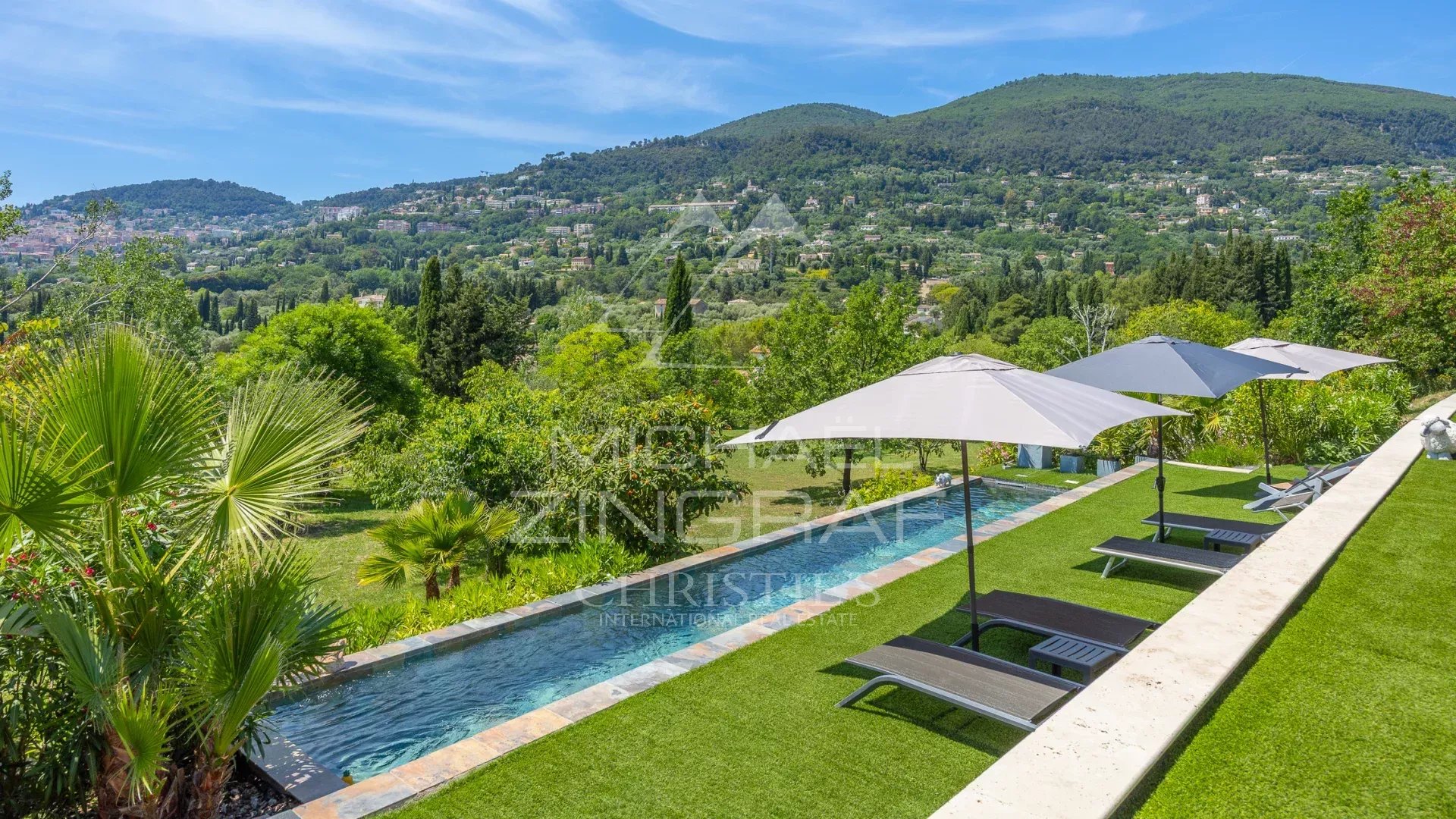 Villa moderne avec piscine à Grasse Vue d'une villa moderne avec piscine et parasols, entourée de verdure à Grasse.