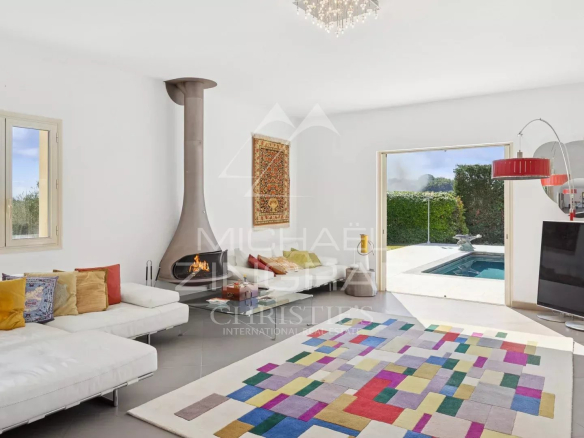 Intérieur d'une villa moderne avec cheminée et accès à la piscine, décoré avec un tapis coloré.