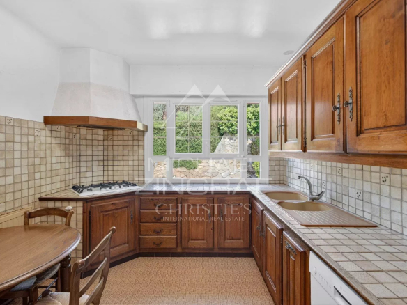 Cuisine d'une villa provençale à Grasse avec meubles en bois et fenêtre donnant sur l'extérieur.
