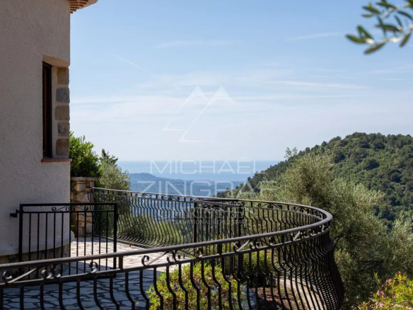 Vue depuis une villa provençale avec balustrade, surplombant les collines et la mer.