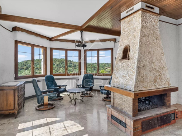 Intérieur d'une villa provençale avec cheminée et vue sur les collines.