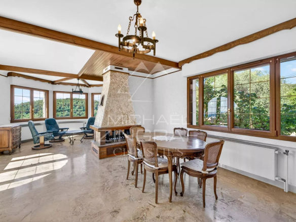 Intérieur d'une villa provençale avec salon lumineux et salle à manger, vue sur la nature.
