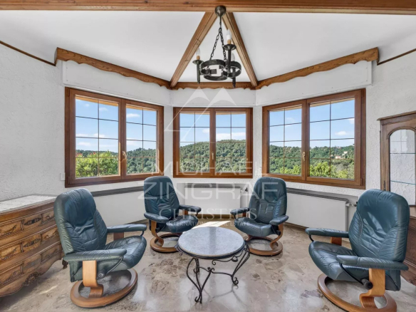 Intérieur d'une villa provençale à Grasse avec vue sur les collines, salon lumineux et mobilier confortable.