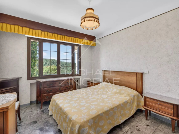 Chambre d'une villa provençale à Grasse avec lit et meubles en bois.