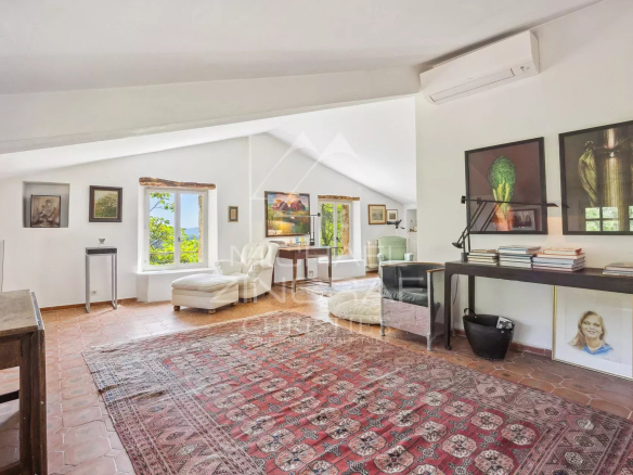 Intérieur d'une propriété avec un salon lumineux, des œuvres d'art aux murs et un tapis au sol.