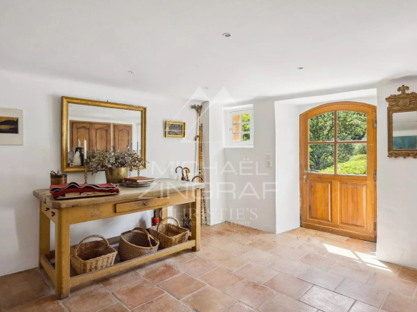 Intérieur d'une bastide en pierre avec table en bois et porte en bois ouvrant sur le jardin.