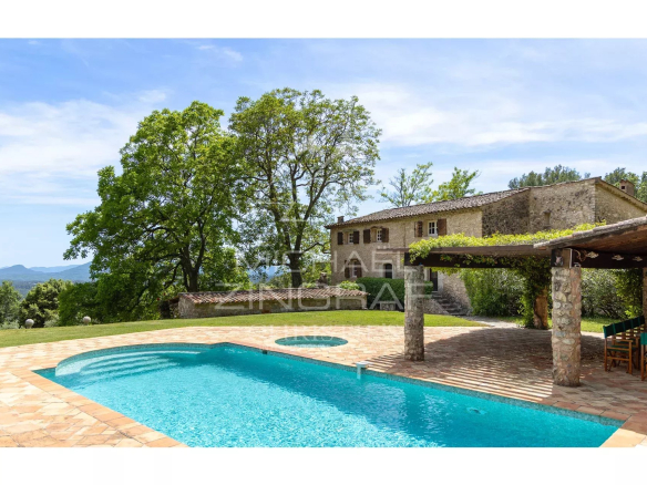 Vue d'une propriété avec piscine et bastide en pierre, entourée d'arbres et de nature à Fayence.