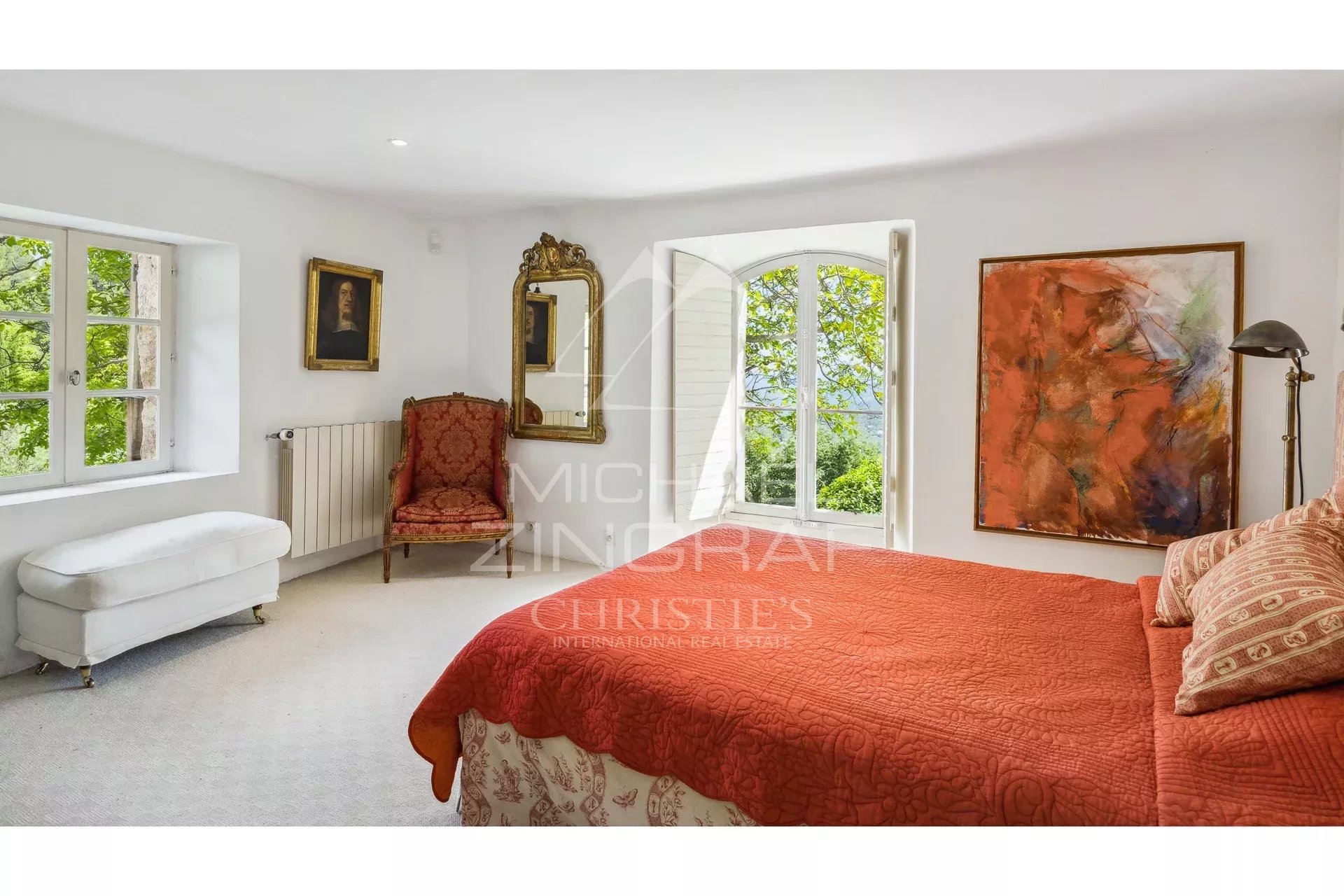 Chambre d’une bastide en pierre à Fayence Chambre d'une propriété en pierre avec vue sur la nature, décorée avec un tableau et un fauteuil ancien.