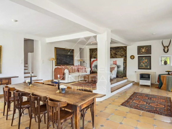 Intérieur d'une bastide en pierre avec salle à manger et salon, décoré avec des œuvres d'art.