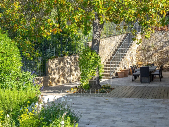 Terrace of a stone villa with sea views in Châteauneuf-Grasse, surrounded by greenery.