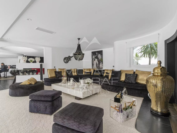 Luxurious open-plan living room with black and gold sectional seating, white rug, and decorative gold vase centerpiece.