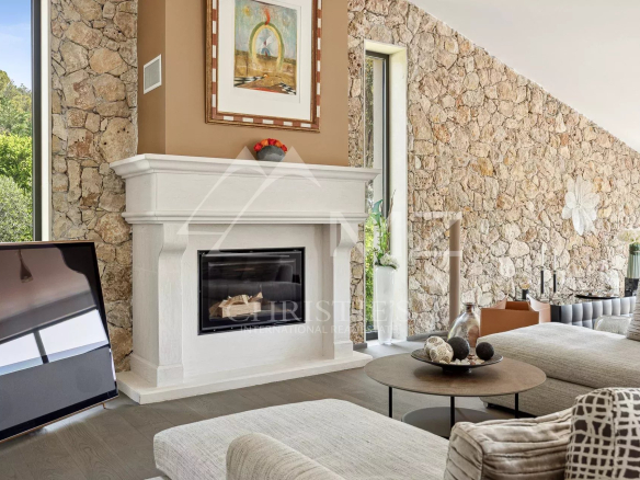 Living room with a white mantel fireplace, stone accent wall, and a large flat-screen TV on the left.