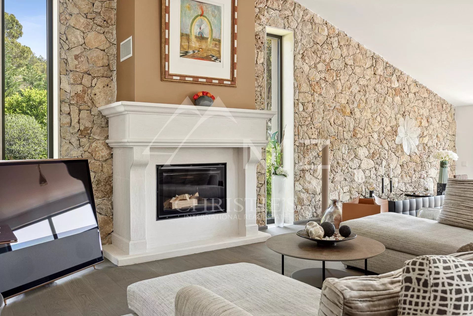 Living room with a white mantel fireplace, stone accent wall, and a large flat-screen TV on the left.