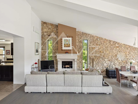 Open-plan living room with a stone feature wall, white fireplace, and a large gray sectional sofa facing a TV.