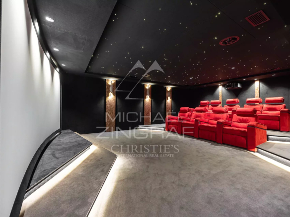 Private home theater with red plush recliner seats in tiered rows, dark walls, and a starry, illuminated ceiling.