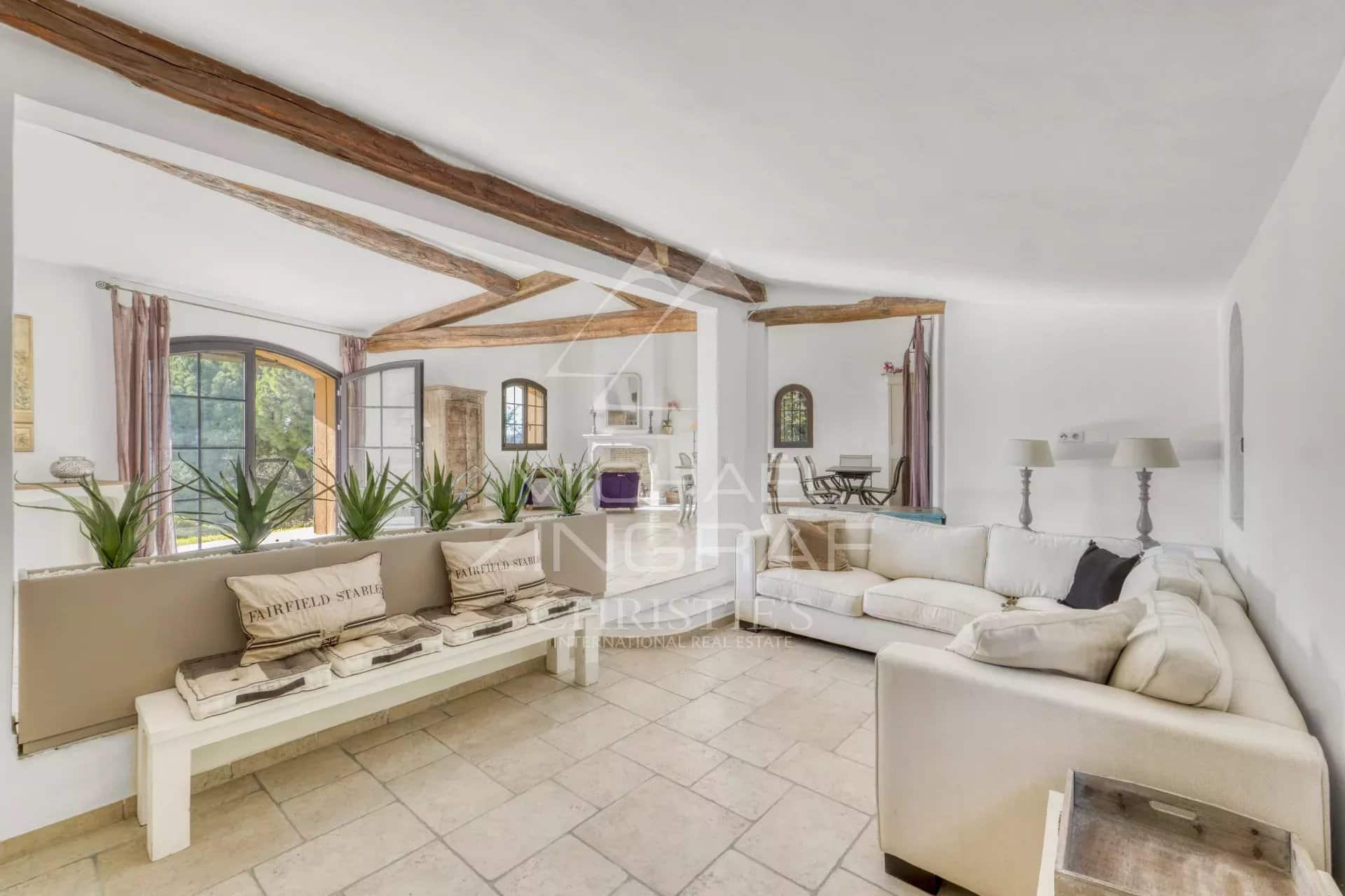 Intérieur d'une villa provençale avec un salon lumineux et des poutres apparentes.