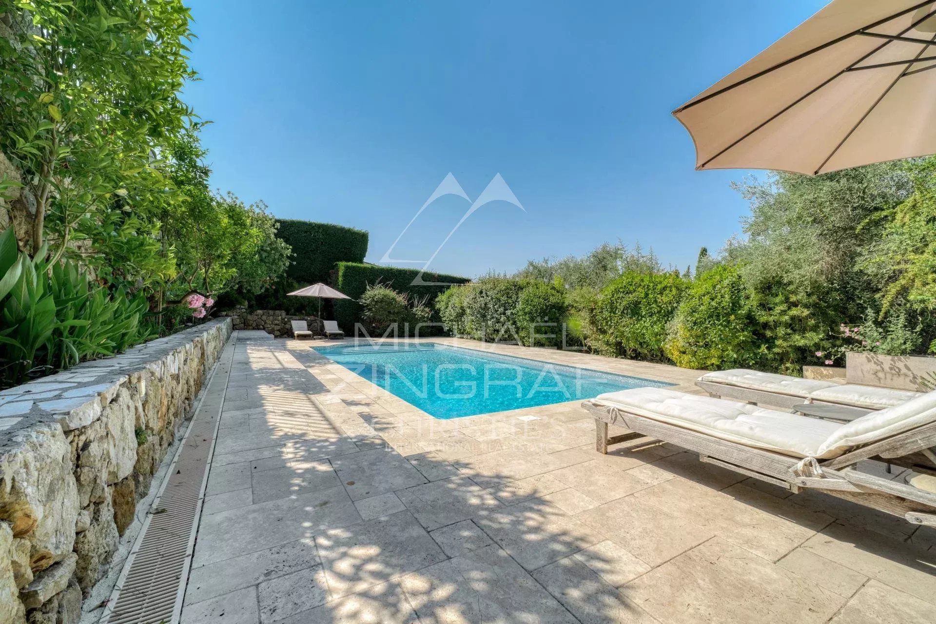 Villa provençale avec piscine et chaises longues dans un jardin verdoyant à Plascassier, Grasse.