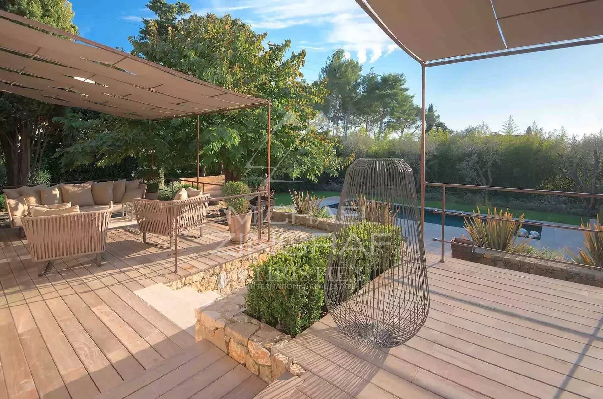 Terrace of a villa in Mougins Wooden terrace with modern furniture and a view of a landscaped garden in Mougins.
