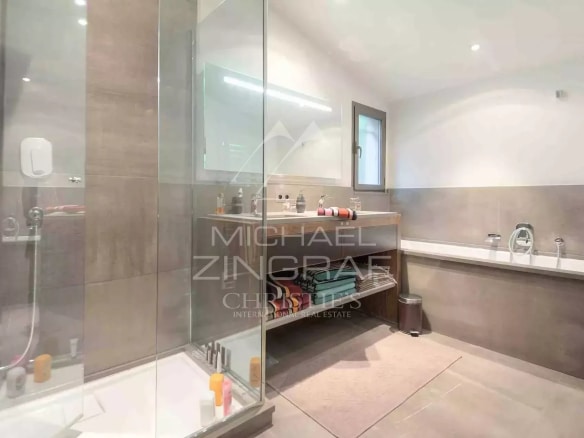 Modern bathroom with glass shower and stone countertop.
