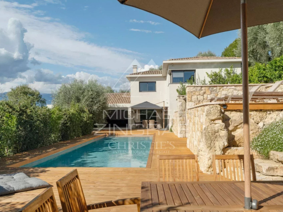 Villa moderne avec piscine et terrasse en bois à Mougins, entourée de verdure.