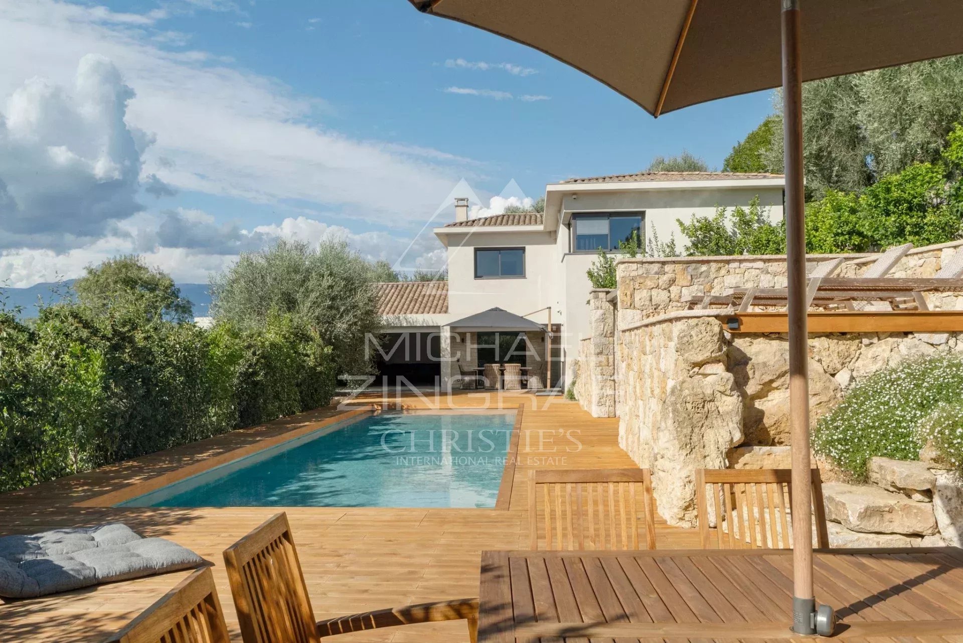 Villa moderne avec piscine et terrasse en bois à Mougins, entourée de verdure.