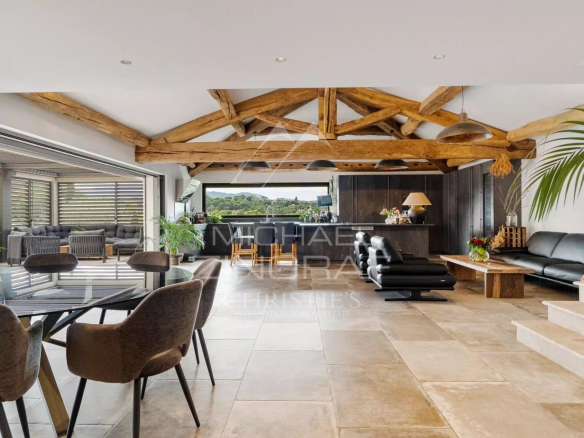 Intérieur d'une villa moderne avec poutres apparentes et espace de vie ouvert.