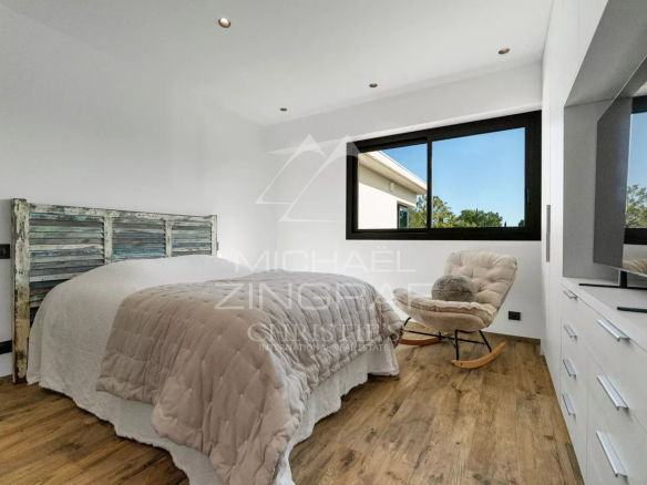 Chambre moderne avec lit et fauteuil, lumière naturelle à Mougins.